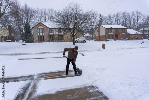 Man clears driveway in snowy midwest winter