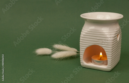 Essential oil in an aroma lamp on a green background, horizontal, copy space