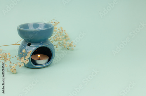 Essential oil in an aroma lamp on a blue background, horizontal, copy space