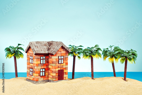 Mock up of a house in the sand. Beach house on a background of sea and blue sky. The concept of buying a home and mortgage. Palm trees and paradise island near the house.