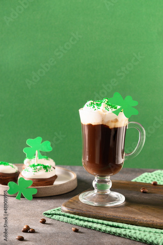 Irish coffee in green cup and special cupcakes for St Patricks Day on green background. Happy st patricks day.
