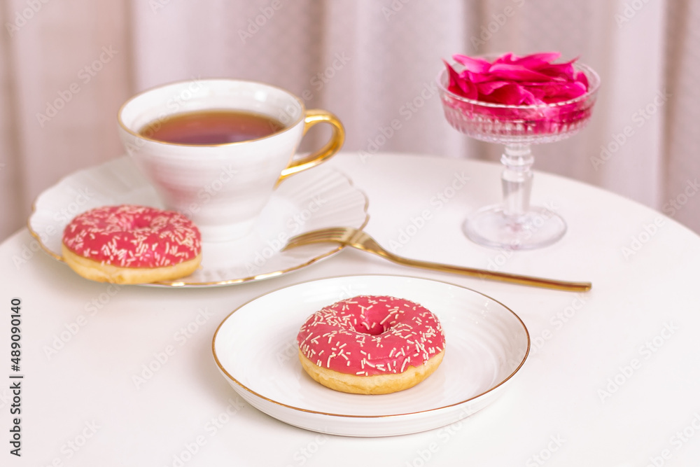 Cup of tea, sweet strawberry donut on golden plate with hydrangea flower Cup of tea, sweet strawberry donut on golden plate with hydrangea flower