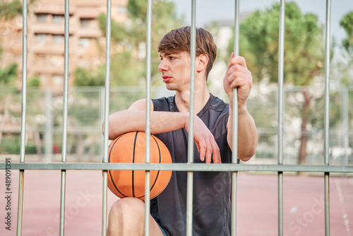 basketball player in sportswear leaning on the court's fence