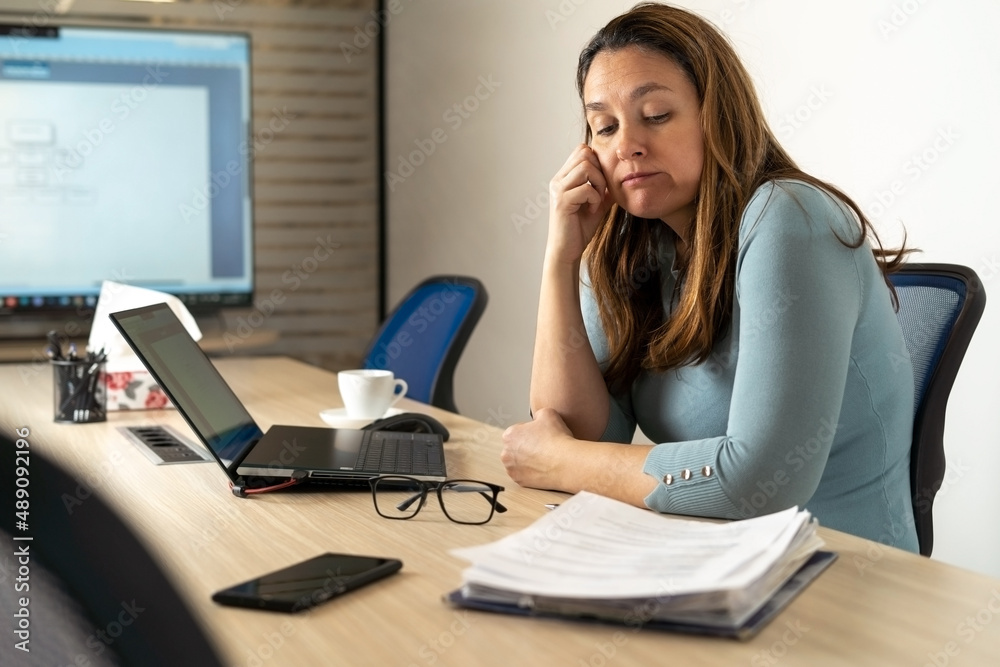 Tired woman with problems sits in the office and thinking how to solve them.Tired facial expression