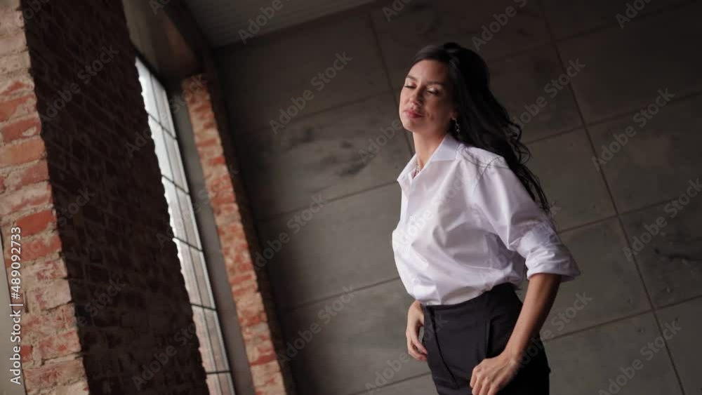 Confident Brunette Business Woman in a White Shirt and Black Trouser Looks at the Camera. Slow Motion. Confident Brunette Business Woman in a White Shirt and Black Trouser Looks at the Camera. Slow Motion.