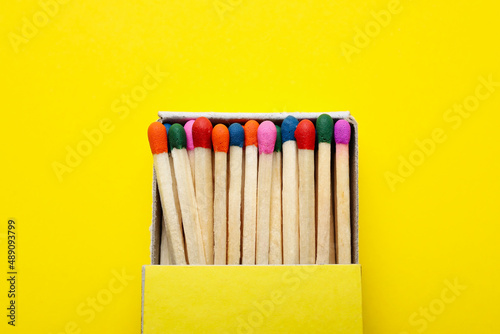 Box with different new matchsticks on yellow background, closeup
