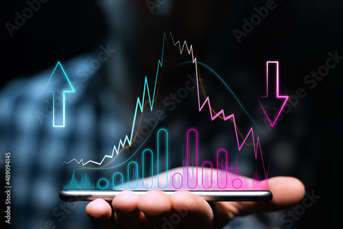 Obraz na plátně Uptrend and downtrend with high volatility, moving averages and volumes on the phone in the investor's hand
