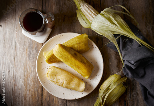 Humitas are savory steamed fresh corn cakes, a traditional Ecuadorian appetizer. It’s accompanied by coffee, on a wooden background.  photo