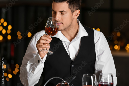 Young male sommelier tastin...