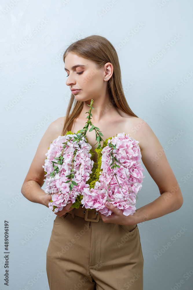 Beautiful confident woman holding fresh spring flowers in her hands. Fresh flowers in the hands of a fair-haired woman Beautiful confident woman holding fresh spring flowers in her hands. Fresh flowers in the hands of a fair-haired woman