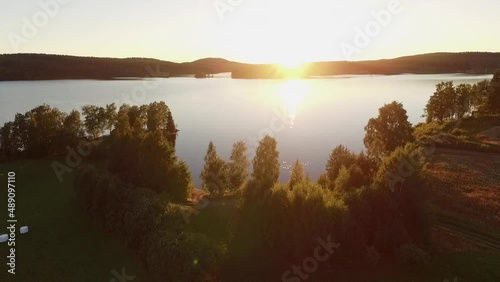 Beautiful sunset over lake and trees with small beach.