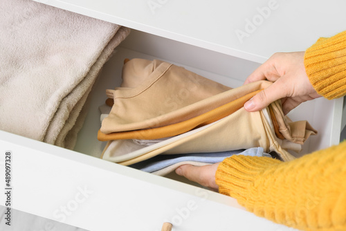 Woman taking baby clothes from drawer, closeup