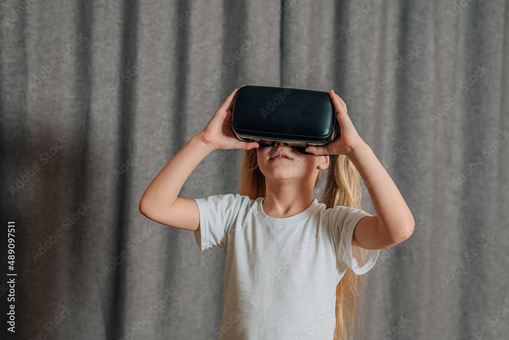 child girl at home in virtual reality VR glasses watching video, playing games. modern children are well versed in technological innovations. generation alpha child girl at home in virtual reality VR glasses watching video, playing games. modern children are well versed in technological innovations. generation alpha