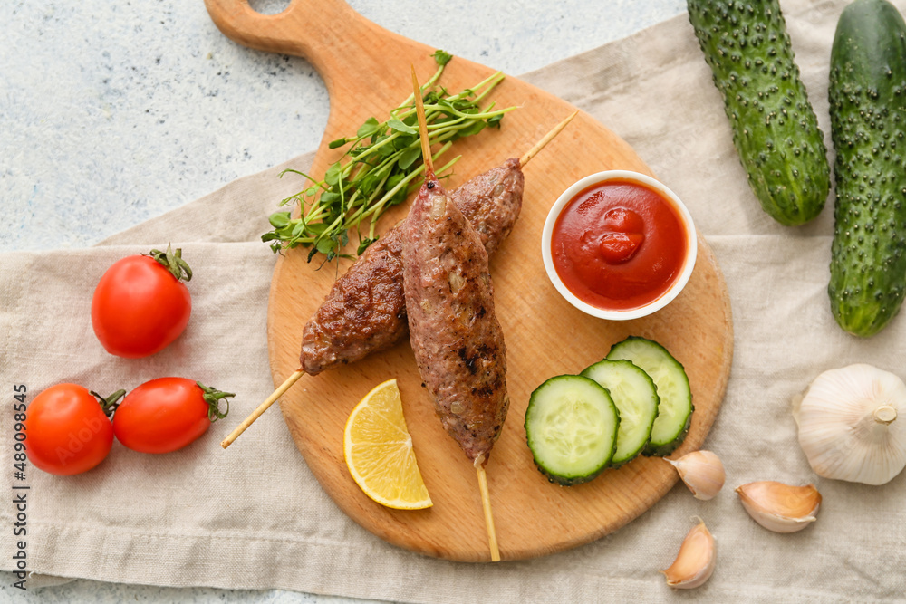 Wooden board of skewers with tasty lula kebab and vegetables on table Wooden board of skewers with tasty lula kebab and vegetables on table