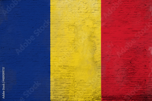 Full frame photo of a weathered flag of Romania painted on a plastered brick wall.