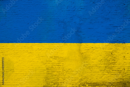 Full frame photo of a weathered flag of Ukraine, painted on a plastered brick wall.