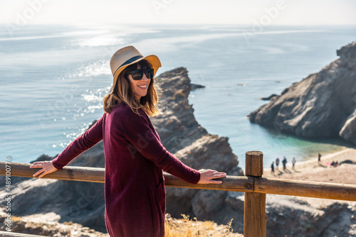 Portrait of a young tourist girl with a hat looking at the beautiful Cala Peñon cut off a virgin and hidden beach in Almería. Mediterranean sea on the coast. Almanzora Caves, Almería