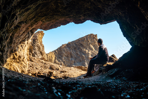 A young tourist sitting in the Almanzora caves, Cala Peñon cut off a virgin and hidden beach in Almería. Mediterranean sea on the coast, Almería