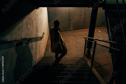 Photography Man descending metal emergency stairs in the shadows of the night