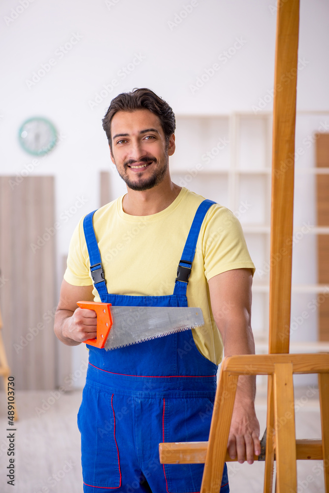 Young repairman repairing easel at home Young repairman repairing easel at home