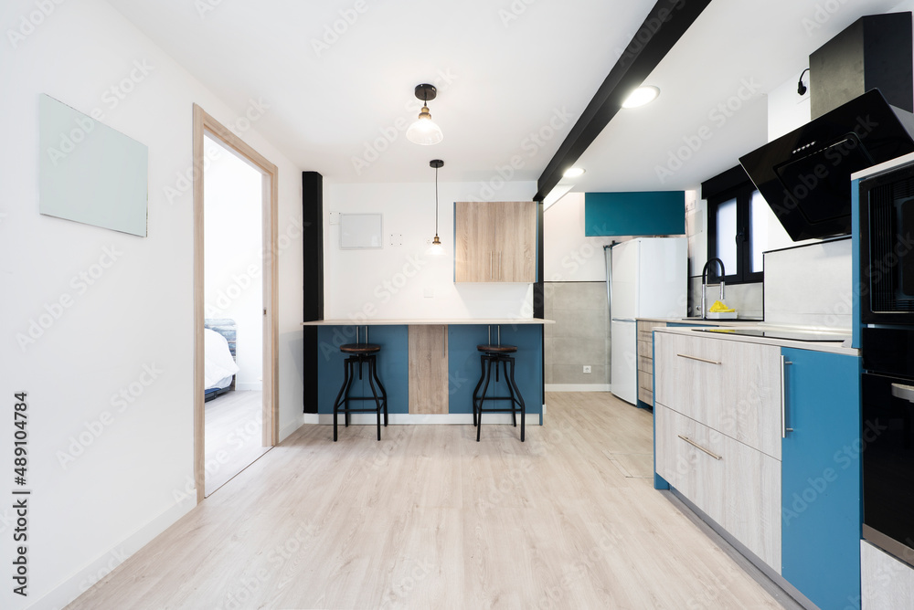 Kitchen with wooden furniture combined with indigo blue and black appliances in a vacation rental apartment
