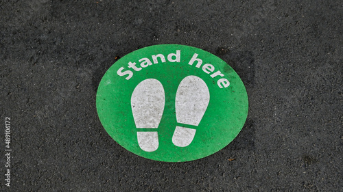 Stand Here Sign Painted on the Pavement at a Railway Station
