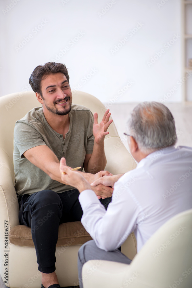Young man visiting old psychologist Young man visiting old psychologist