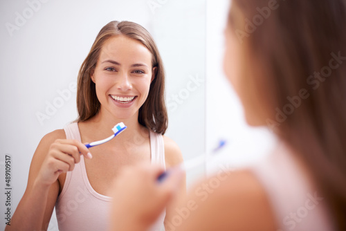 Taking care of her smile. A young woman brushing her teeth.