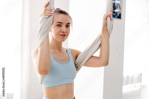 woman 25 years old is hanging using hammock for yoga. Lady wearing in light blue sportswear
