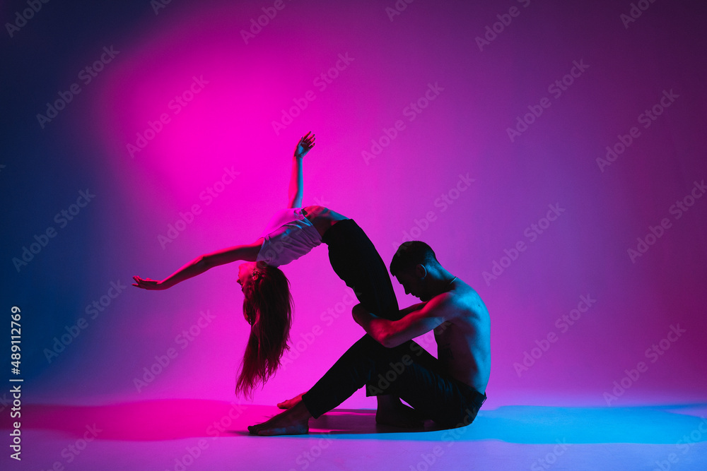 support.Strong flexible man holding the girl by the legs,flexible woman