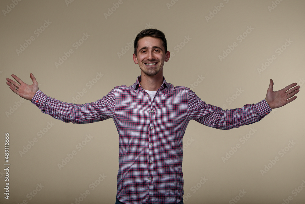 Portrait of young happy laughing man which celebrating with hands raised to the sides. Successful happy man in casual shirt. Portrait of young happy laughing man which celebrating with hands raised to the sides. Successful happy man in casual shirt.