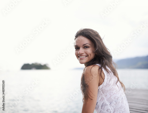 Taking the time out to focus on me. Portrait of an attractive young woman sitting on a jetty by the lake.