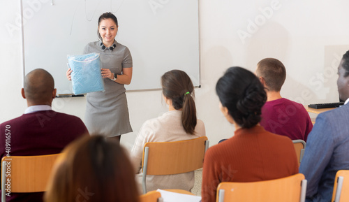 Female coach presents the product in audience at the business training