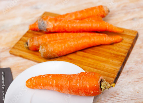 Pile of fresh raw winter carrots on wooden table