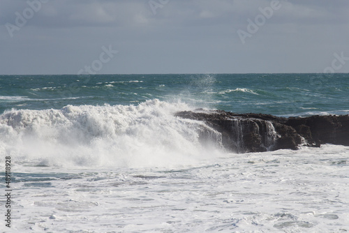 Waves are crashing on a group of stones. © daisy_y