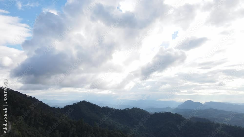 Top view soft sunlight shines through the clouds. Big fluffy clouds covered the green mountains. Top view soft sunlight shines through the clouds. Big fluffy clouds covered the green mountains.