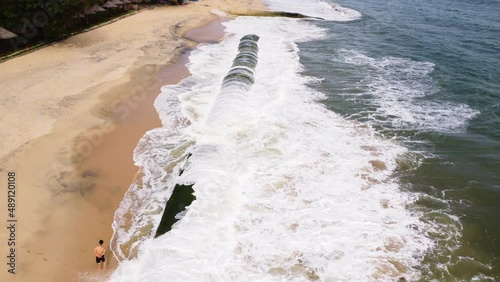 Mossy geo tube on sandy coastal beach of Vietnam to protect land from ocean waves photo