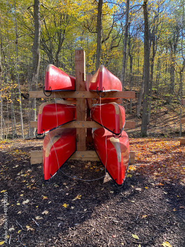 Canots rouges sur un support en bois en forêt à l'automne. Location d'embarcation nautique, canoë de rivière, rabaska dans un parc national. Centre de plein air et de camping. photo