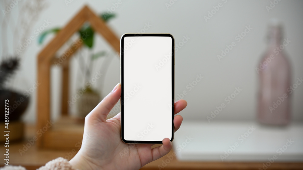 A female hands holding a smartphone white screen mockup A female hands holding a smartphone white screen mockup