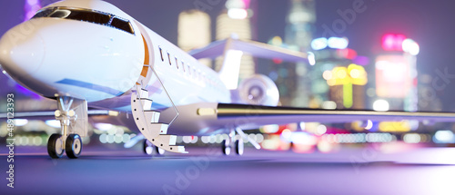 Private jet parked on runway over blurred city night lights in the background.