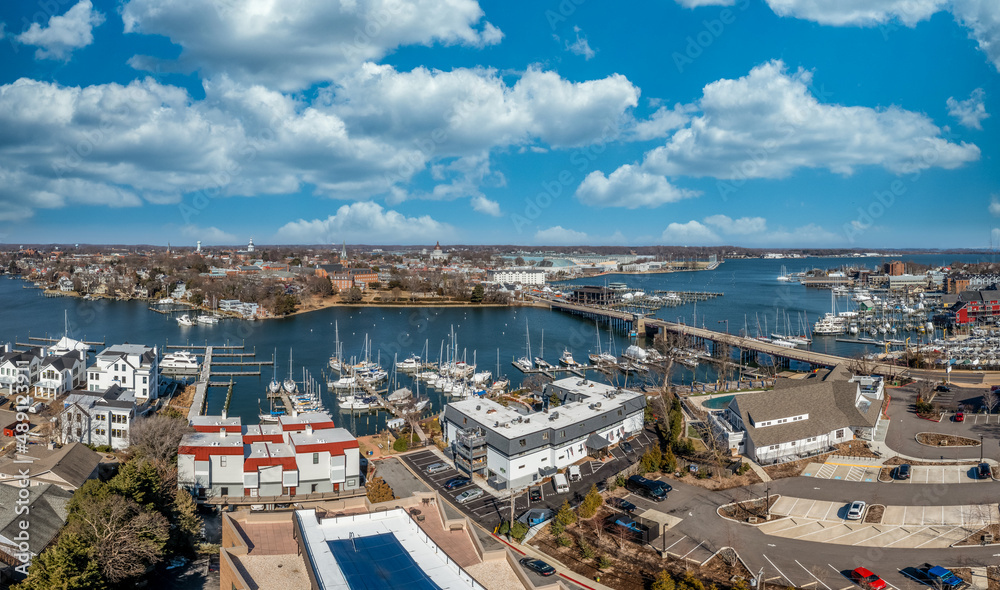 Aerial panorama of Annapolis harbor with luxury sail boats docked in the marina, drawbridge crossing the creek, Maryland state house and Naval Academy, luxury water side houses