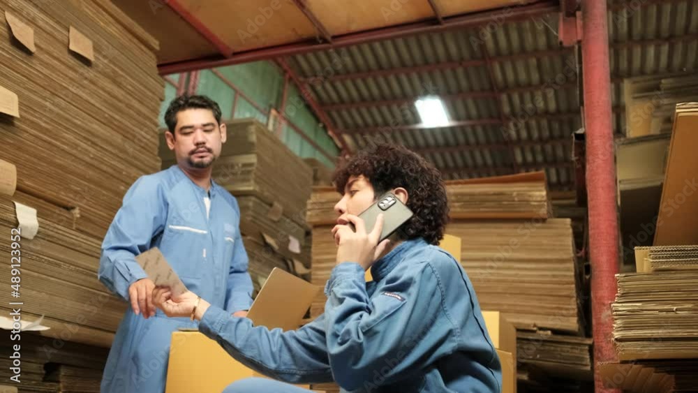 Two safety uniform workers and colleagues use laptop and mobile phone to check shipment orders stock at parcels warehouse, paper manufacture factory for packing industry, logistic transport service. Two safety uniform workers and colleagues use laptop and mobile phone to check shipment orders stock at parcels warehouse, paper manufacture factory for packing industry, logistic transport service.