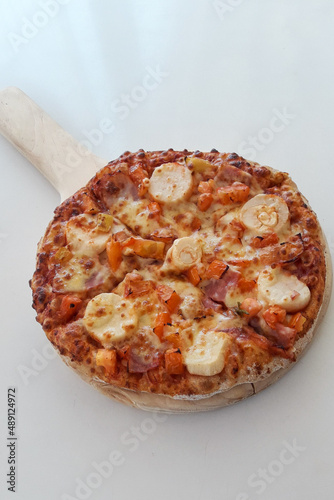 Pizza pequeña sobre tabla de madera, napolitana, queso, tomate, jamón 