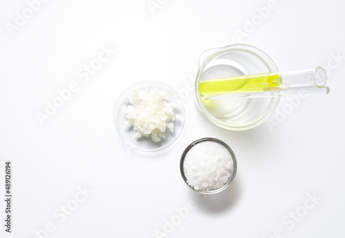 Nickle chloride liquid in test tube, Flake salt in Chemical Watch Glass and Cetyl esters wax in glass container. Chemicals ingredients on laboratory table. Top View