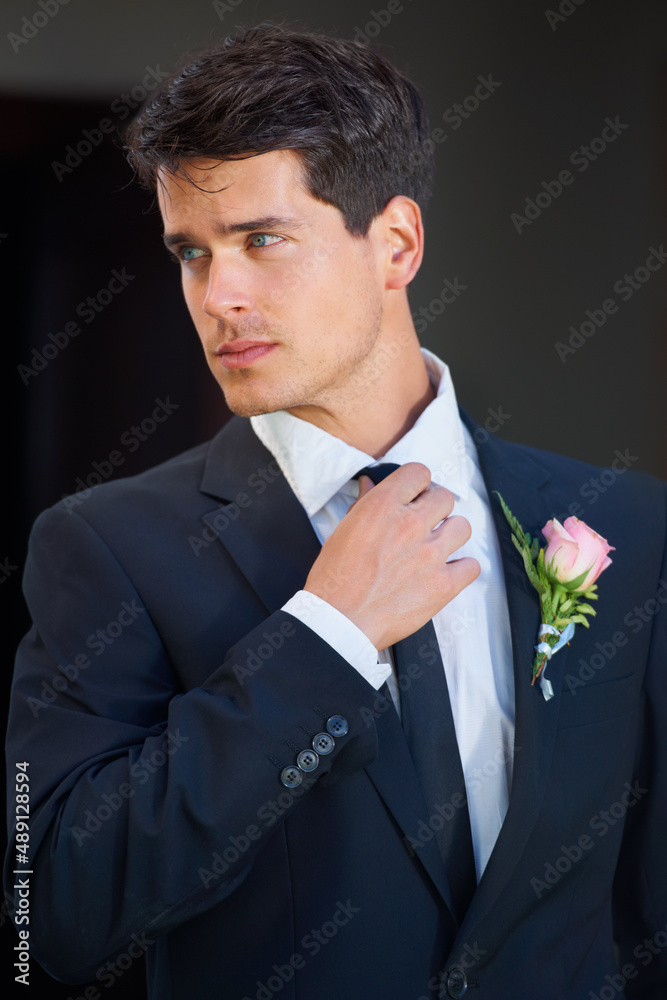 Looking great on his big day. A handsome groom wearing a pink rose on his jacket isolated on a black background. Looking great on his big day. A handsome groom wearing a pink rose on his jacket isolated on a black background.