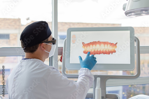 Male dentist analyzing a virtual model of a female patient
