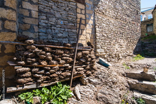 dung fuel for heating lies against a stone wall