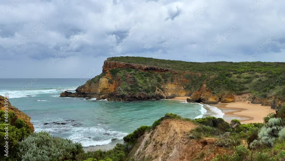 Beautiful inlet along the Great Ocean Road coastline, grey skies and private beach surrounded by cliffs and eroded hills Beautiful inlet along the Great Ocean Road coastline, grey skies and private beach surrounded by cliffs and eroded hills