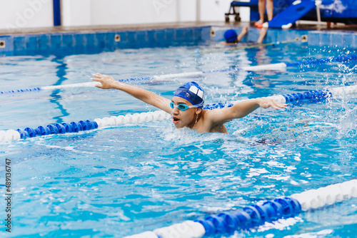 latin young man swimmer athlete wearing cap and goggles in a swimming training holding On Starting Block In the Pool in Mexico Latin America