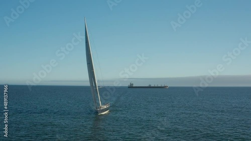 Wally 100ft yacht sailing towards camera, Cargo ship in distance, Atlantic Ocean
